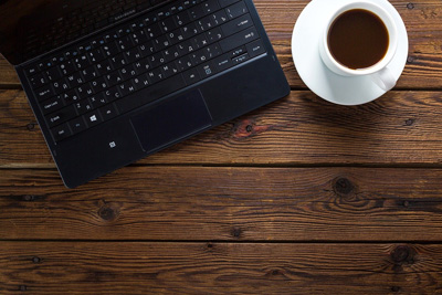 Ein Notebook und eine Tasse Kaffee auf einem Holztisch
